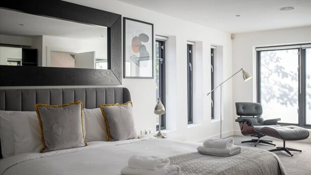 A modern bedroom with a large bed, a desk, and a chair.