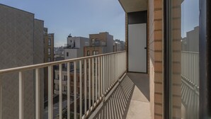 A balcony with a metal railing, a door, and a view of neighboring buildings.