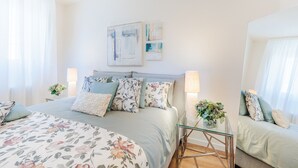 Un dormitorio moderno con una cama grande, dos mesitas de noche con lámparas y una obra de arte en la pared.