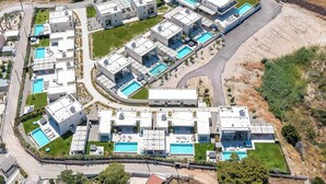 An aerial view of a modern residential complex with multiple buildings, swimming pools, and landscaped areas. - Villa Trapezia Pearl (Kolympia)
