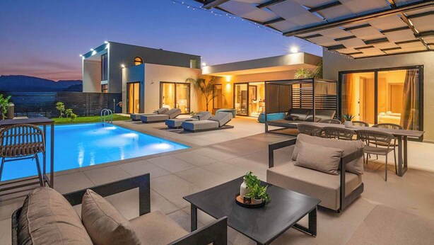 A modern outdoor living area with a pool, seating, and a covered patio. - Villa Trapezia Pearl (Kolympia)