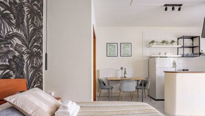 A hotel room with a bed, a desk, and a kitchenette.