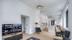 A modern living room with a flat-screen TV, a sofa, a coffee table, and a dining area with a lamp. - Château de la Roche (Vourles)
