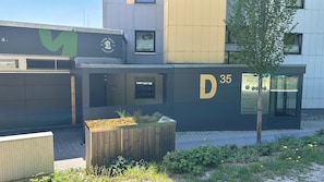 A modern building with a large 'D 35' sign, a small window, and a wooden planter with plants.