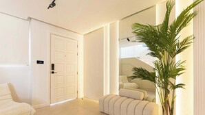 A modern hotel room with a large mirror, a potted plant, a sofa, and a door. - Villa Zalex Springs 14 Luxury Living with Private Pool (Dubai)