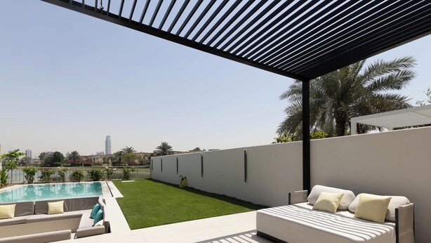 Ein moderner Außenbereich mit Pool, einer Couch und einer Pergola.