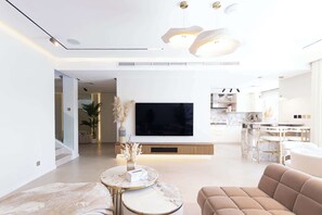 Un salon moderne avec un téléviseur à écran plat, une table basse en marbre et un canapé beige.