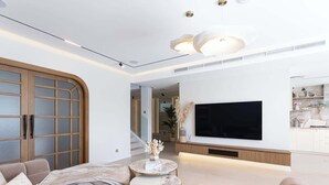 Ein modernes Wohnzimmer mit einer Couch, einem Couchtisch und einem flachbildfernseher an der Wand.