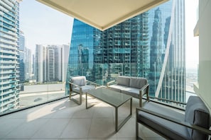 Enjoy panoramic city views from the spacious balcony with a glass table and seating areas.