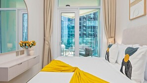 A hotel room with a bed, a window, a balcony with a view, and a vase with flowers on the nightstand. - Bright & Beautiful 1BR at Missoni Urban Oasis (Dubai)