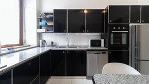 A modern kitchen with black cabinets, a stainless steel sink, a microwave, an oven, and a dishwasher. - Italianway Easy - Palazzi 6 C (Milan)