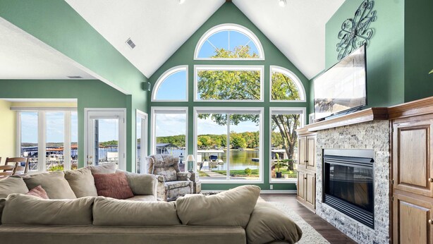 A spacious living room with a large window, a fireplace, and a view of a lake.
