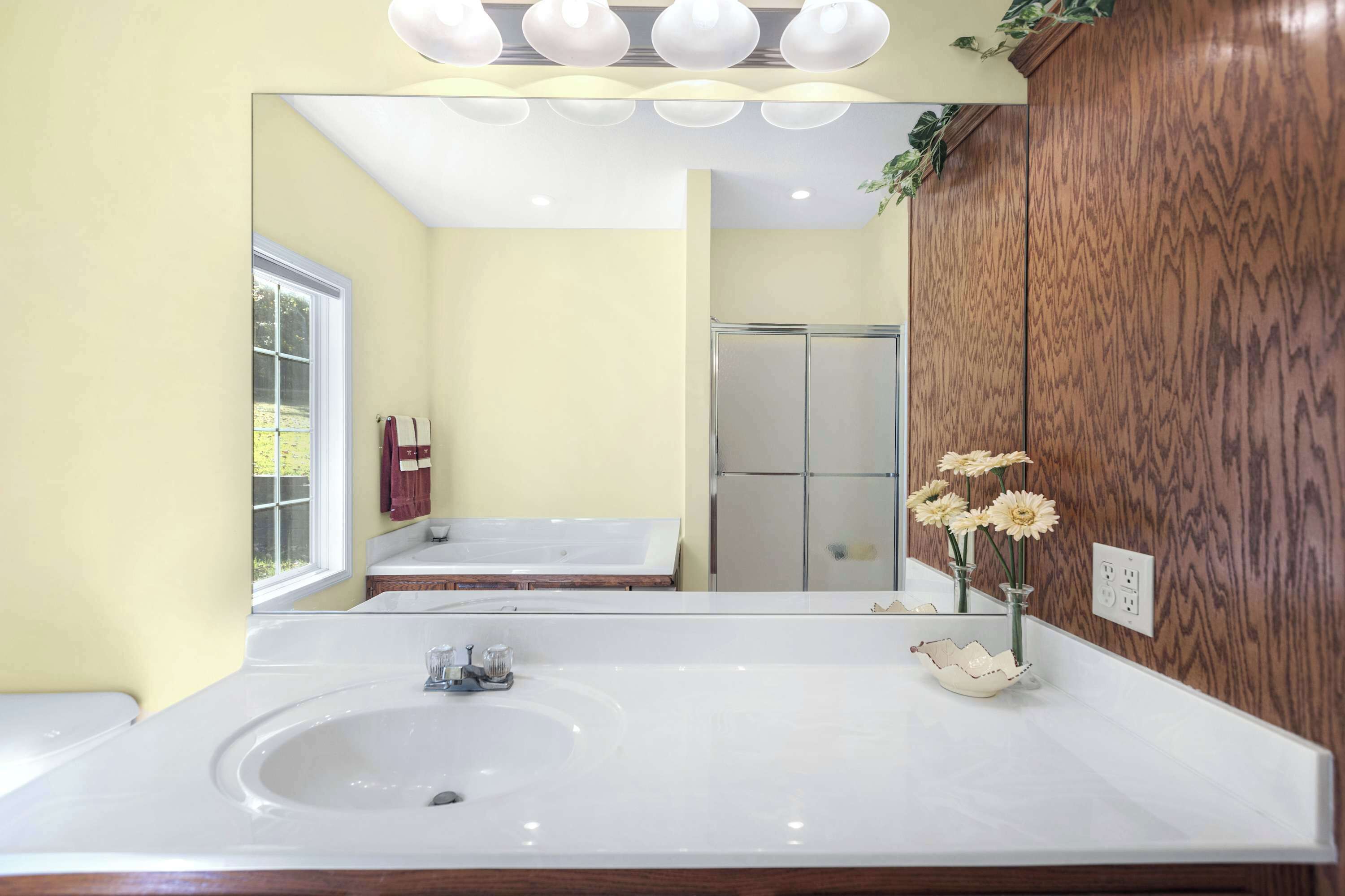 Un baño con un lavamanos grande de color blanco, un espejo encima y un mueble de tocador de madera.