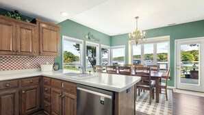 A kitchen with wooden cabinets, a stainless steel dishwasher, and a dining area with a table and chairs.