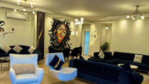 Un área de estar moderna con un sofá grande, dos sillones, una mesa de centro y un mural decorativo.