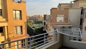 Una terraza en la azotea con césped artificial verde, baranda de metal y vistas a edificios vecinos.