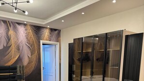 Un dormitorio moderno con cama, armario y un gran mural de plumas en la pared.