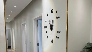 Un pasillo moderno con un reloj de pared decorativo, un tapete y plantas en macetas.