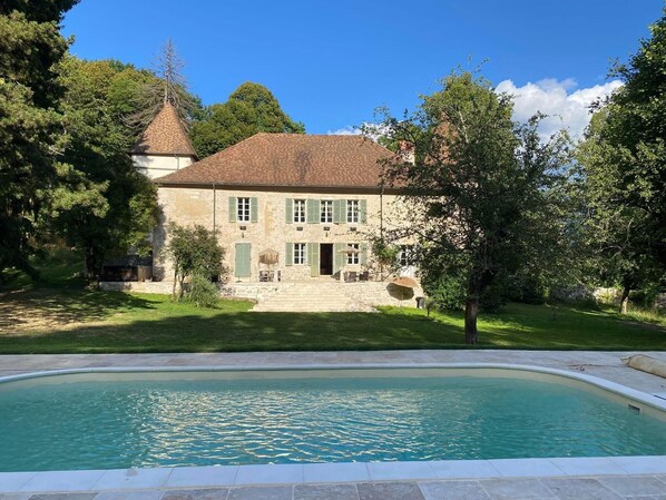 Um edifício de pedra com piscina em frente.