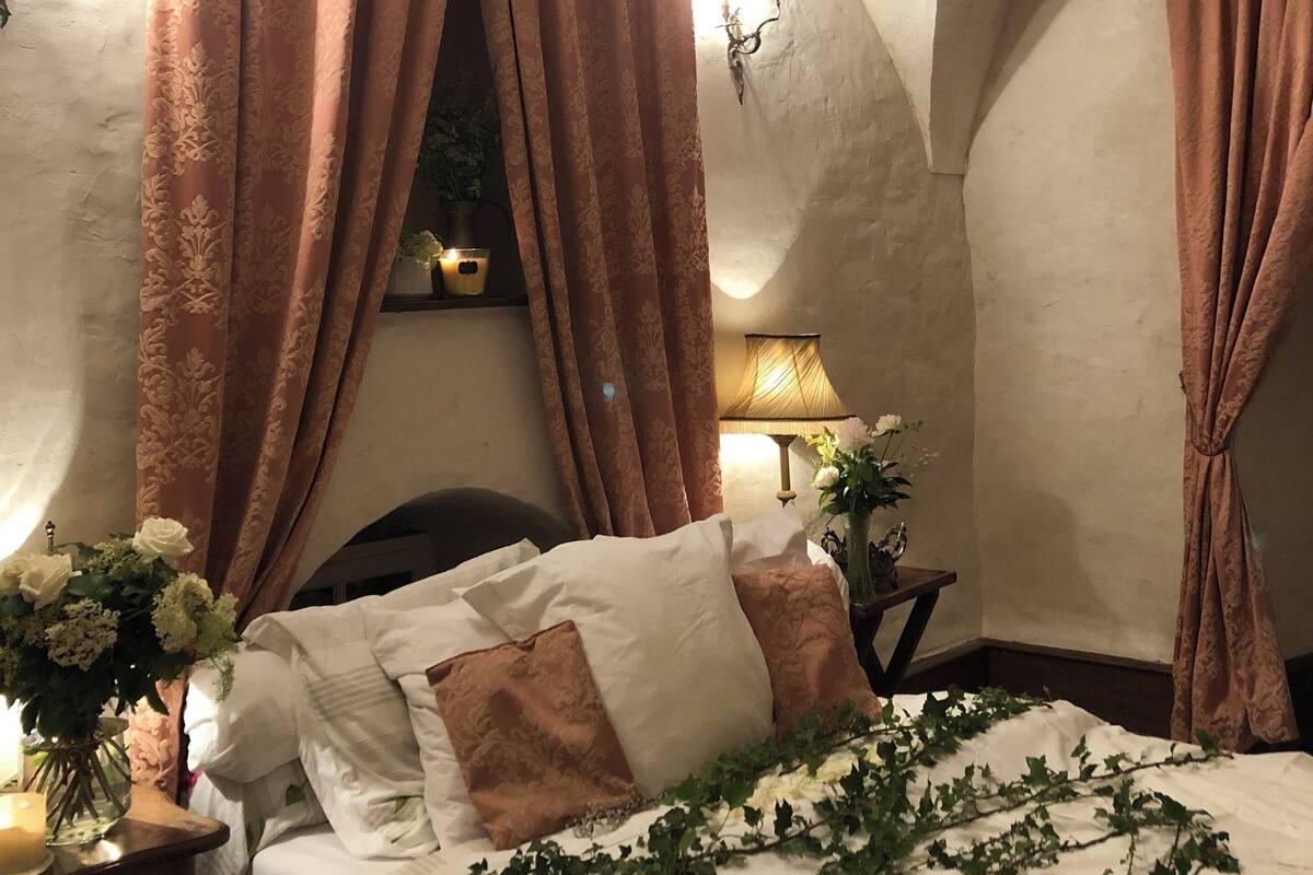 A bedroom with a curved ceiling, a bed with white and brown bedding, and brown curtains.