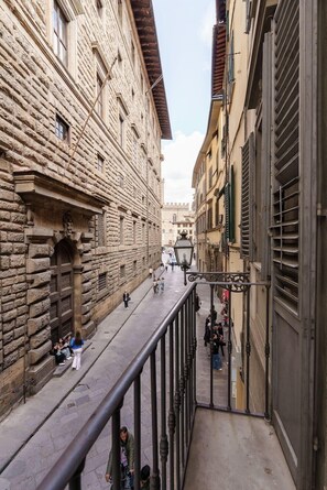 Un carrer estret amb edificis de pedra, una zona per a vianants i una barana metàl·lica.