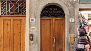 A building with two wooden doors, numbered 10 and 8, and a row of handbags outside. - Uffizi & Palace View - Florence Dolce Vita (Firenze)