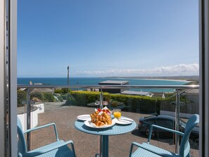 A balcony with a table set for breakfast, overlooking a coastal view. - Skysail (St Ives)