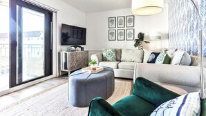 Una sala de estar moderna con sofá, reposapiés y un televisor de pantalla plana montado en la pared.