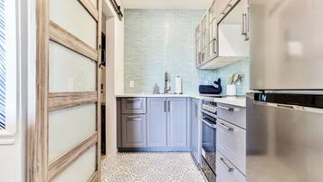 A modern kitchen with grey cabinets, a stainless steel refrigerator, and a patterned floor.