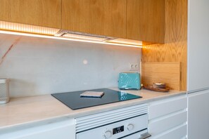 A modern kitchen with wooden cabinets, a white countertop, a built-in stove, and a small toaster.