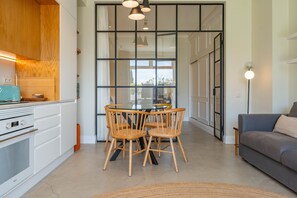 A modern kitchen with white cabinets, a built-in oven, and a dining area with a round table and four wooden chairs.