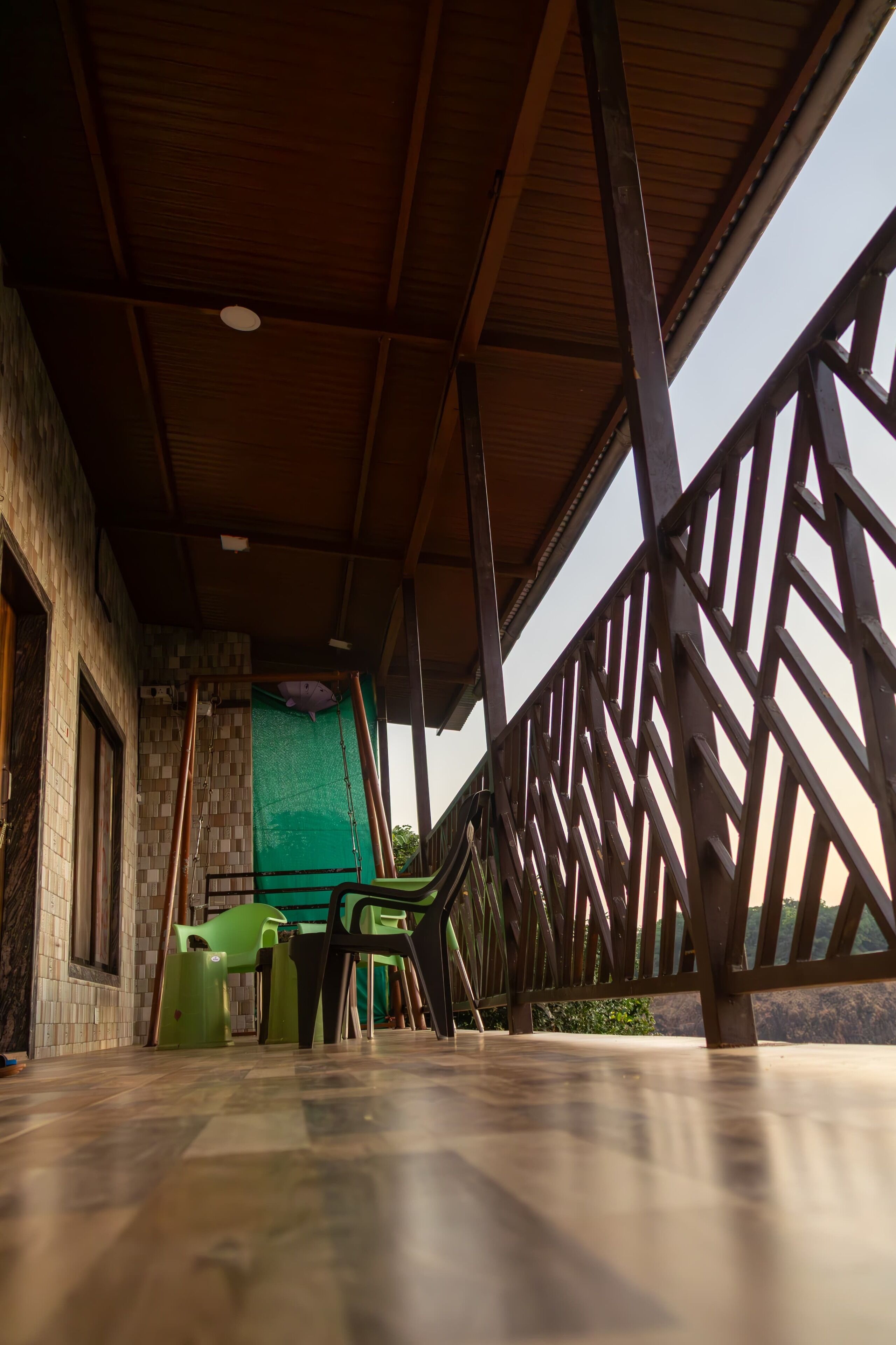 A covered outdoor area with a wooden ceiling, a green wall, and a metal railing.
