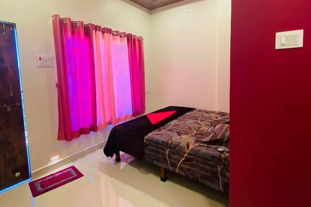 A room with a bed, a ceiling fan, and a red wall.