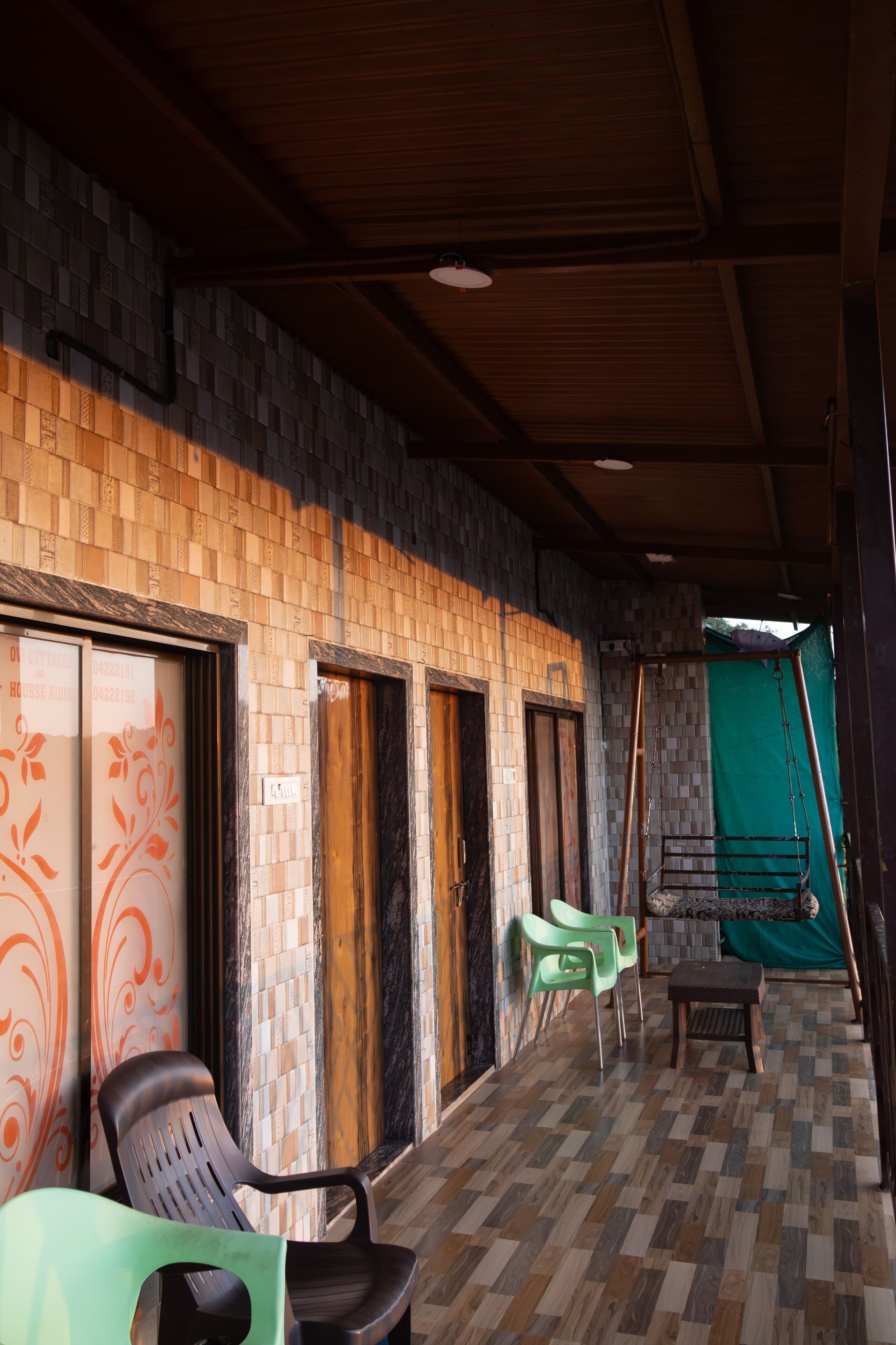 A room with a tiled floor, wooden ceiling beams, and a green swing.