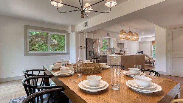 A modern dining room with a wooden table set for six, surrounded by black chairs.