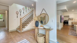 Ein modernes Interieur mit einer Holztreppe, einem Konsolentisch mit Dekoration und einer Küche im Hintergrund.