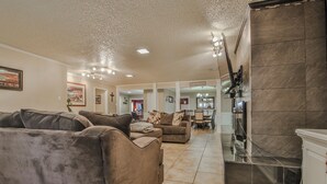 A spacious living area with a fireplace, a dining table, and a kitchen area with a tiled backsplash. - Amazing 4,500 sq ft 2-story home in King's Gate. Perfect for large groups! (Lubbock)