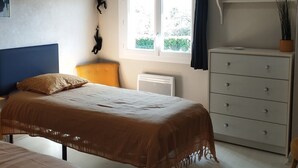 Une chambre à coucher avec un lit, une commode, une fenêtre et un tableau accroché au mur.