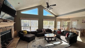 A spacious living room with a fireplace, large windows, and a dining area. - Lake It Easy - Waterfront Getaway With 7 Bedrooms! (Rocky Mount)