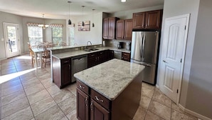 A spacious kitchen with granite countertops, stainless steel appliances, and dark wooden cabinets. - Lake It Easy - Waterfront Getaway With 7 Bedrooms! (Rocky Mount)