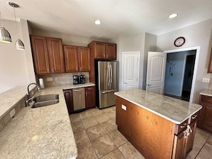 A kitchen with granite countertops, stainless steel appliances, wooden cabinets, and a clock on the wall. - Lake It Easy - Waterfront Getaway With 7 Bedrooms! (Rocky Mount)