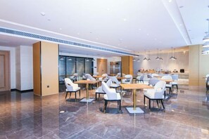 A modern dining area with tables and chairs, a kitchen in the background, and a polished floor. - Keli Select Zero Pressure Sleep Hotel (Zhijiang Sports Center) (Zhijiang)