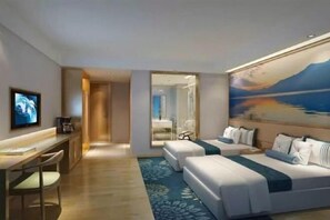 Relax in a spacious room with a large bed, desk, and comfortable seating area, offering a view of the outdoors.