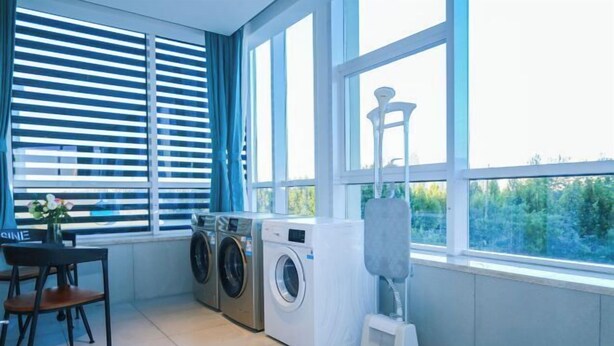 A laundry room with a washing machine, dryer, and a chair. - Keli Select Zero Pressure Sleep Hotel (Zhijiang Sports Center) (Zhijiang)