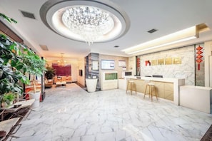 A hotel lobby with a marble floor, a reception desk, a chandelier, and a TV screen. - Keli Select Zero Pressure Sleep Hotel (Zhijiang Sports Center) (Zhijiang)