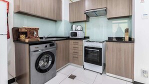 A compact kitchen with a washing machine, microwave, and oven.