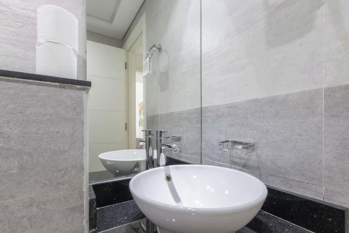 Un baño moderno con un lavamanos blanco, un espejo y una cabina de ducha con mampara de cristal.