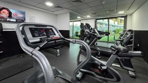 A gym with treadmills, a digital display, and a window view.