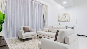 Un salon moderne comprenant un canapé, une table basse et un coin repas avec des chaises.