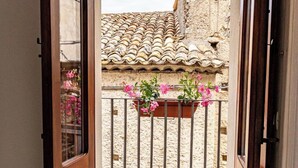 A balcony with a tiled roof, a wrought iron railing, and a flower box with pink flowers. - Alborghetto2 (Gerace)